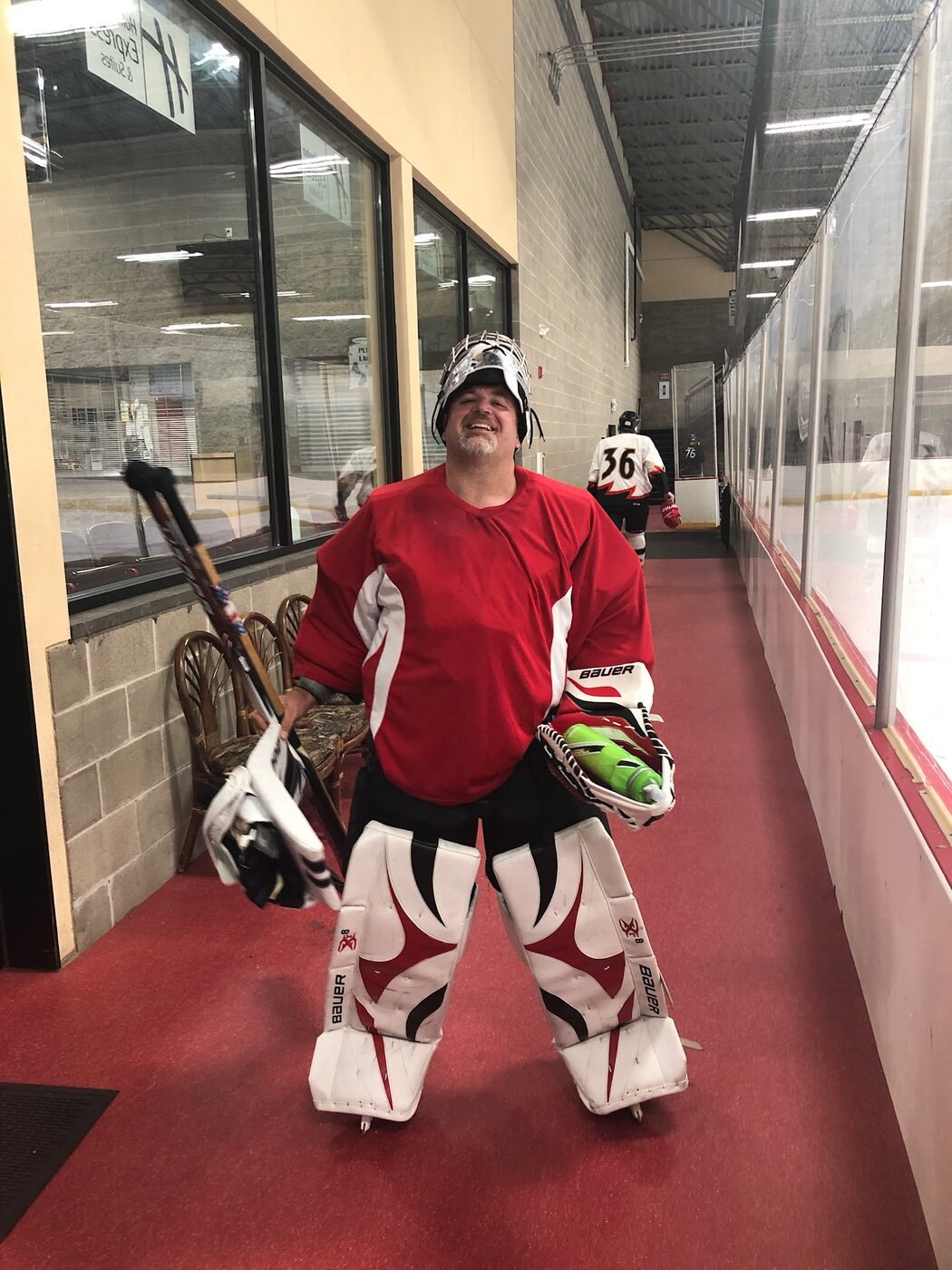Mike Baker in full goalie gear, grinning in the rink hallway