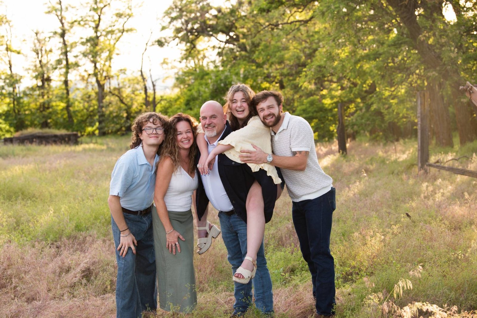 The Baker family in a field in June 2026 — Mike, Kellie, and their three adult children laughing together.