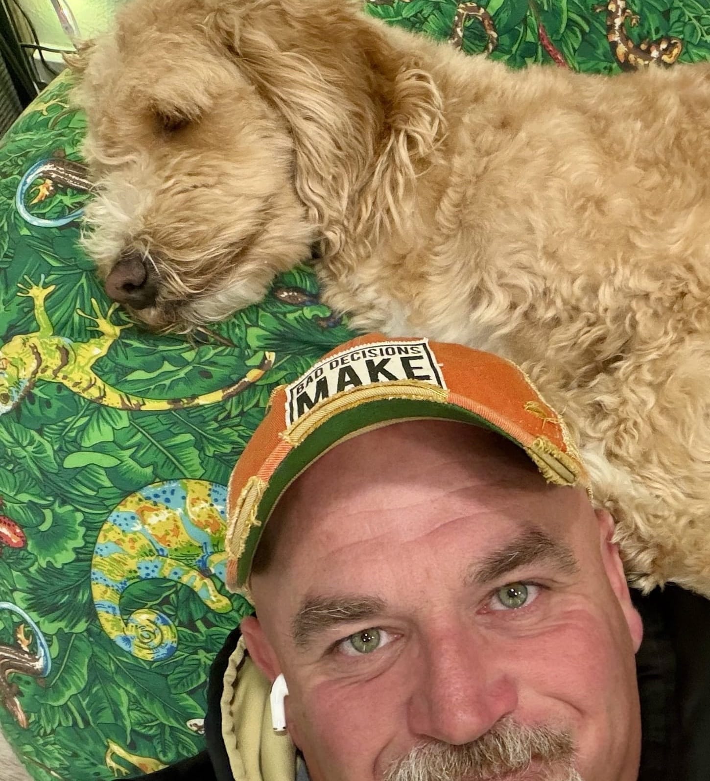 Mike Baker in a ball cap and hoodie, with Gus the dog asleep on the beanbag behind him
