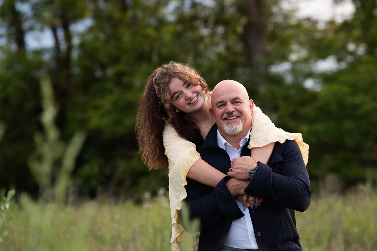 Samantha with her arms around her dad, Mike Baker, both laughing in a field