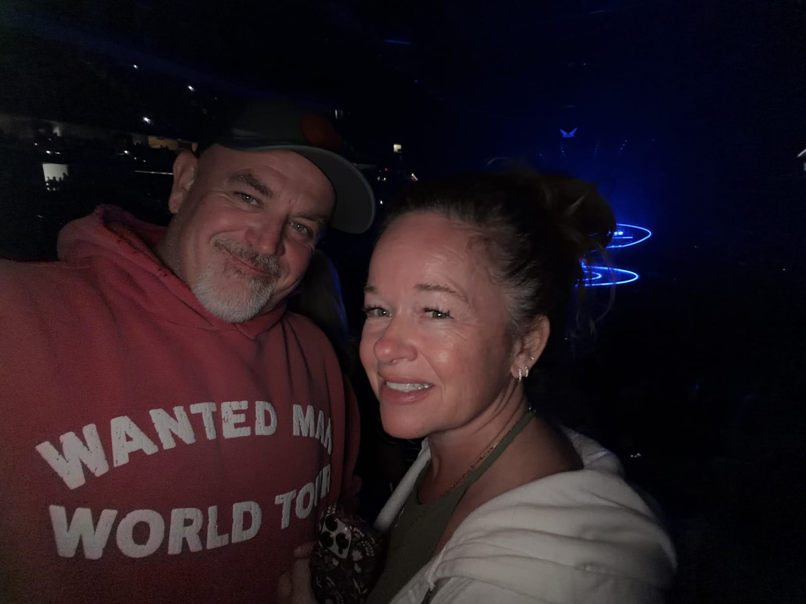 Mike and Kellie Baker smiling together in the dark at a concert, blue stage lights behind them